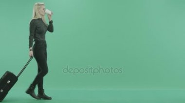 Bagaj ve kahve ile yürüyen genç sarışın kadın