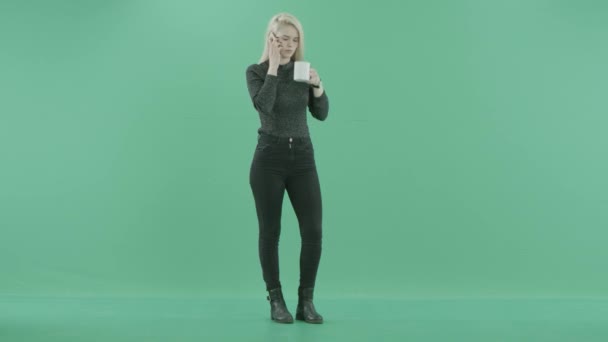 Woman stands talking on the phone with a mug of tea — Stock Video