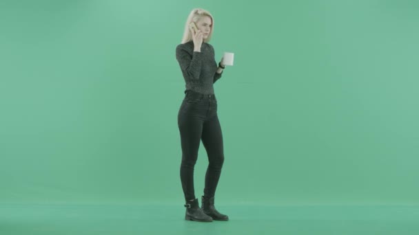 Жінка п'є чай, розмовляючи по телефону — стокове відео