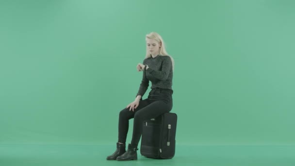 A girl is sitting on the luggage and waiting — Stock Video