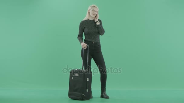 Une jeune femme blonde est debout avec des bagages et un téléphone — Video