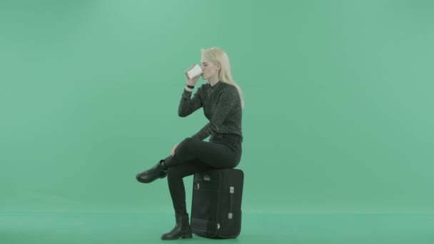 Een vrouw drinkt koffie zittend op de Bagage — Stockvideo