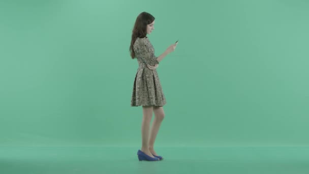 Een leuk meisje is permanent met een telefoon in handen — Stockvideo