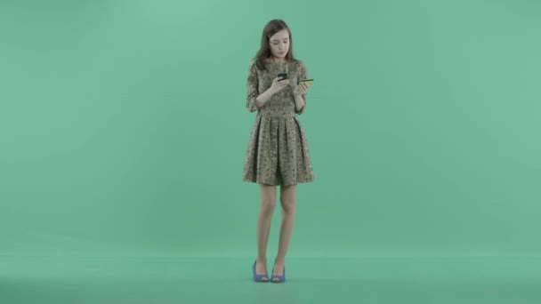 Uma menina está segurando um cartão de plástico e um telefone — Vídeo de Stock