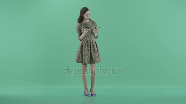 Eine junge Frau hält eine Karte und ein Telefon in den Händen — Stockvideo