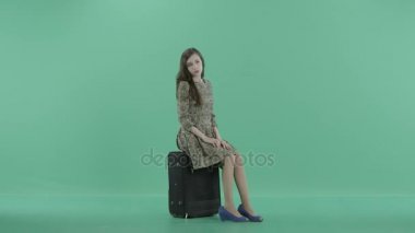 sıkılmış bir kız bavula oturuyor