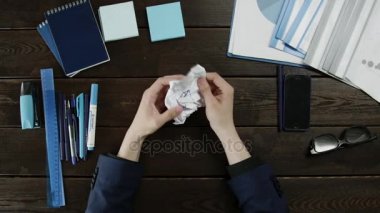 Bir adamın buruşturulmuş bir kağıt yaprağının unwrapping Üstten Görünüm