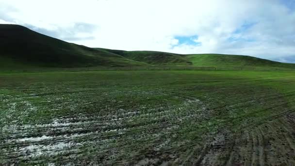 Disparo de helicóptero de tierra sucia cerca de montañas verdes — Vídeos de Stock