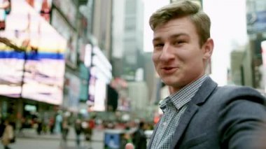 Genç mutlu adam bir kamera önünde onu ve uzakta bir şey üzerinde işaret tutuyor