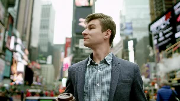 Young man on Times Square with a cup of coffee looking on his watch and walking away — Stock Video