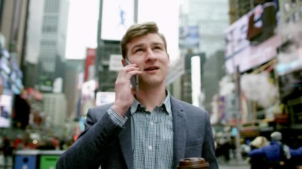 Ung man dricka te och prata över hans smartphone på Times Square — Stockvideo
