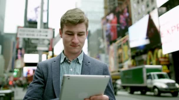 Mladý šťastný muž je SMS zpráva na svůj tablet pc na Times Square