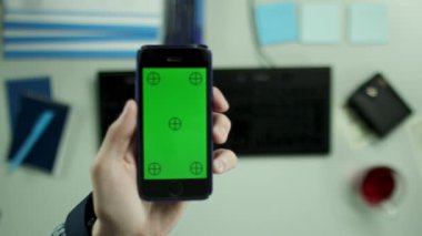 Yukarıdan aşağıya görünümü. Bir adam banka hesabını kontrol etmek için cep telefonu kullanıyor