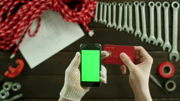 Top view of a man purchasing something with his cellphone and a credit card — Stock Video