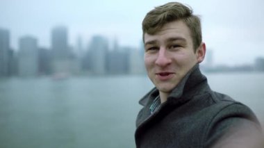 Holding kamera önünde onun yüz ve elini sallayarak ve Manhattan Adası'na işaret eden genç adam