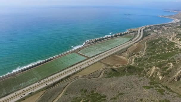 Tiro aéreo de estrada ao lado da costa do oceano Pacífico e campo de plantação — Vídeo de Stock