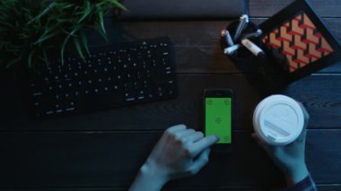 Yukarıdan aşağı onun smartphone ile yeşil ekran üzerinde kahve yudumlarken swiping adam vurdu