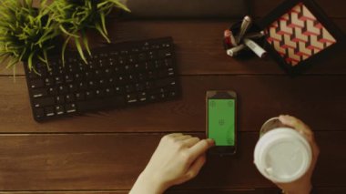 Yukarıdan aşağıya kahve yudumlarken onun smartphone ile yeşil ekran kullanan adam görünümünü