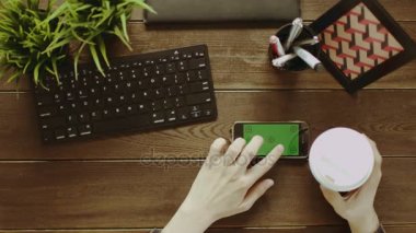 Adam onun akıllı telefon Yeşil perde-in kahve yudumlarken swiping havai çekim