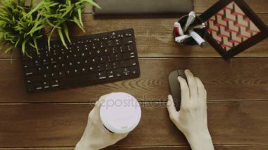 Yukarıdan aşağı diğer elinde kahve ile bilgisayar fare kullanan adam vurdu