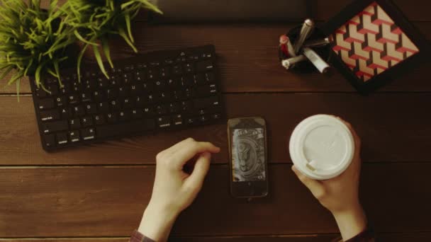 スマート フォンで写真を見て、お茶を飲む男のオーバー ヘッド ショット — ストック動画