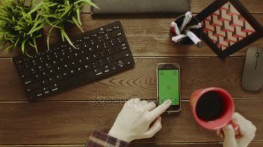 Yukarıdan aşağı atış adam smartphone ile yeşil ekran kullanarak ve çay içme