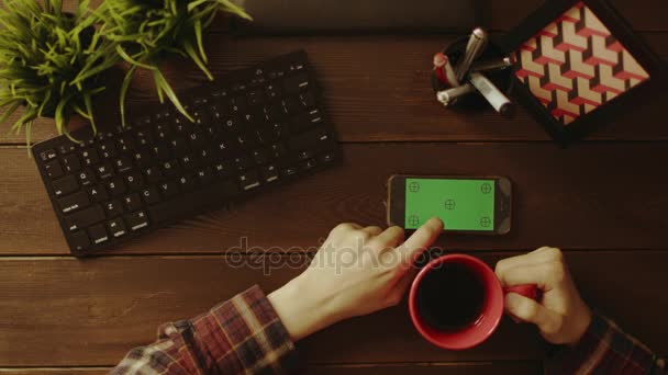 Top down shot of male using smartphone with green screen and drinking coffee — Stock Video