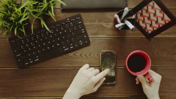 Top-Down-Aufnahme eines Mannes, der während der Kaffeepause Fotos auf dem Smartphone anschaut — Stockvideo