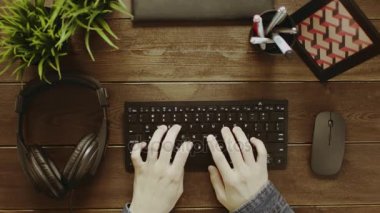 Yukarıdan aşağı atış adam klavyede yazarak ve kulaklıklar koyarak