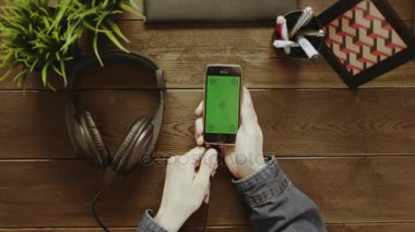 Yukarıdan aşağıya smartphone ile yeşil ekran kullanarak ve kulaklıklar koyarak adam görünümünü