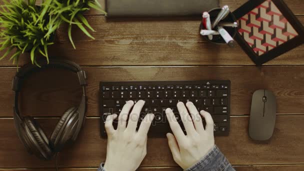 Aufnahme von oben, wie Mann auf Tastatur tippt und Kopfhörer aufsetzt — Stockvideo