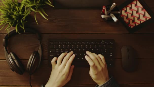 Vista aérea del hombre escribiendo en el teclado y poniéndose auriculares — Vídeos de Stock