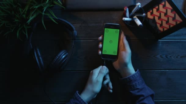 Vista aérea del hombre usando un teléfono inteligente con pantalla verde y poniéndose auriculares — Vídeos de Stock