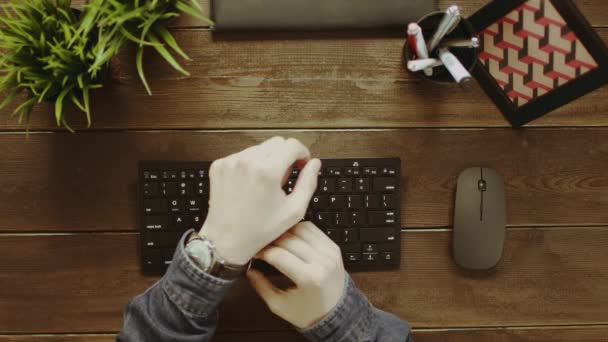 Plan du haut vers le bas de l'homme reportant sa montre et tapant sur le clavier — Video