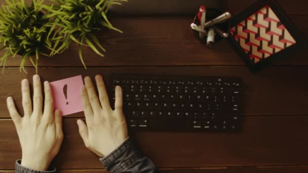 Overhead view of man sticking sticky note with exclamation point on table before working — Stock Video