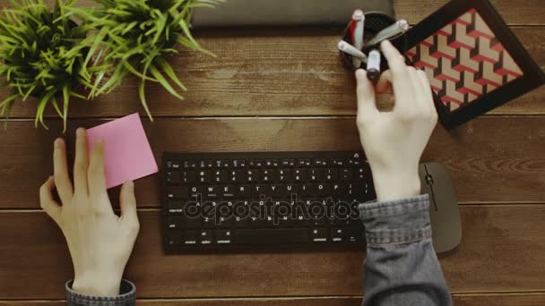 Tiro de arriba hacia abajo del hombre escribiendo en el teclado y pegando nota con palabras "Buen trabajo" en el marco — Vídeo de stock