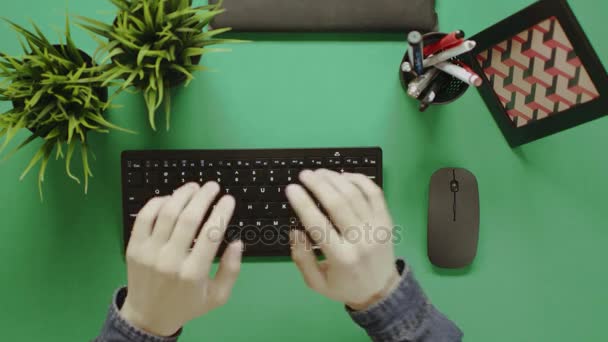 Toppbilde av en mann som skriver fort på tastatur på et bord med kromatøkkel – stockvideo