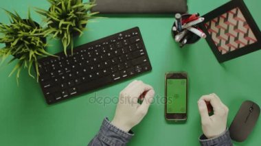 Bir adam ile masada chroma anahtar yeşil ekran ile smartphone kullanarak yukarıdan vurdu