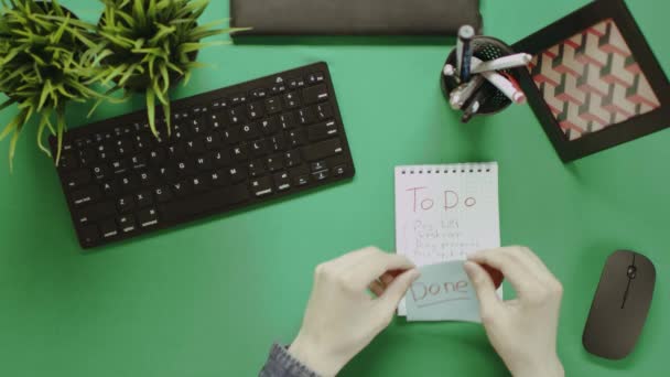 Overhead shot of man sticking reminder on notepad and showing thumbs to camera — Stock Video