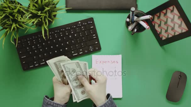 Top down shot pria menghitung uang tunai dengan notepad di meja — Stok Video
