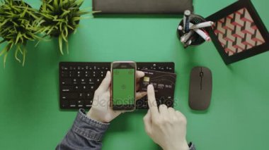 Yukarıdan aşağı atış adam kredi kartı tutan ve onun smartphone kullanarak