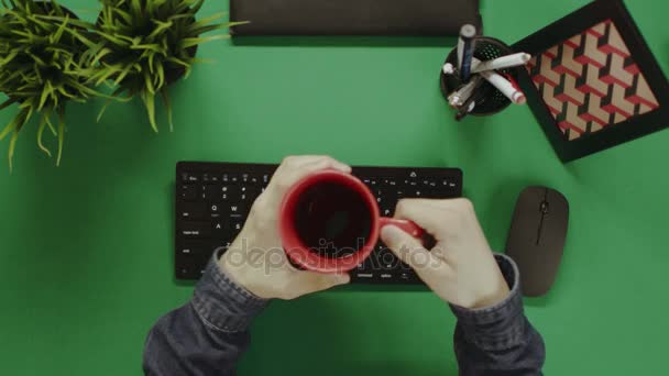 Yukarıdan aşağı atış adam kahve içme ve klavyede yazmadan önce parmaklarını kadar Isınma — Stok video