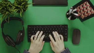 Yukarıdan aşağı atış adam bir klavyede yazarak ve kulaklıklar koyarak