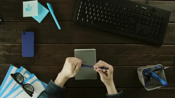 Чоловік переписує інформацію з комп'ютера в блокнот . — стокове відео