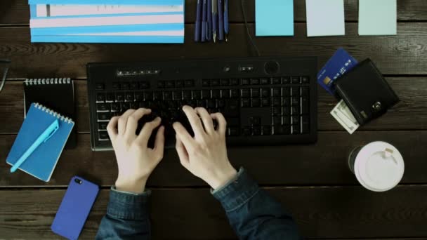 En mann skriver på et datamaskintastatur på pulten sin . – stockvideo