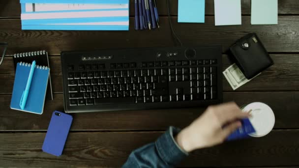 Ένα κάθισμα άνθρωπος κοντά στο πληκτρολόγιο του υπολογιστή στο γραφείο του και καταργεί την κάρτα κάτω από το πορτοφόλι. — Αρχείο Βίντεο