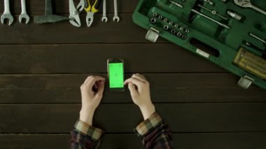 Bir adam araç kutusu yakınındaki bir masada oturur ve telefonunu kullanır.