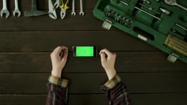 Bir adam araç kutusu yakınındaki bir masada oturur ve telefonunu kullanır.