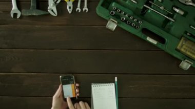 Araç kutusu yakınındaki bir masada bir adam oturuyor ve ve notepad ile Hesap makinesinde dikkate alır.
