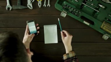 Araç kutusu yakınındaki bir masada bir adam oturuyor ve ve notepad ile çok hızlı hesap makinesi.